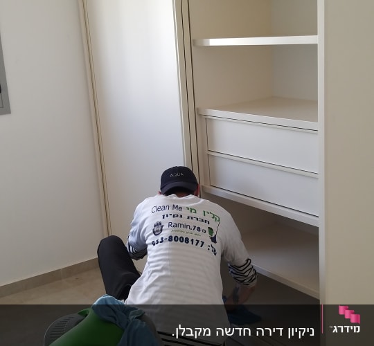 אדם מנקה מדפים עם שואב אבק ומטלית
